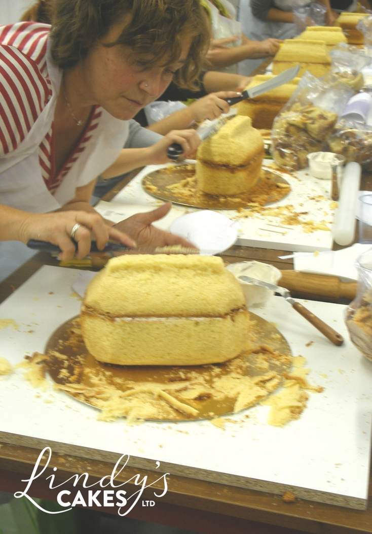 Students carving handbags to shape from a square cake