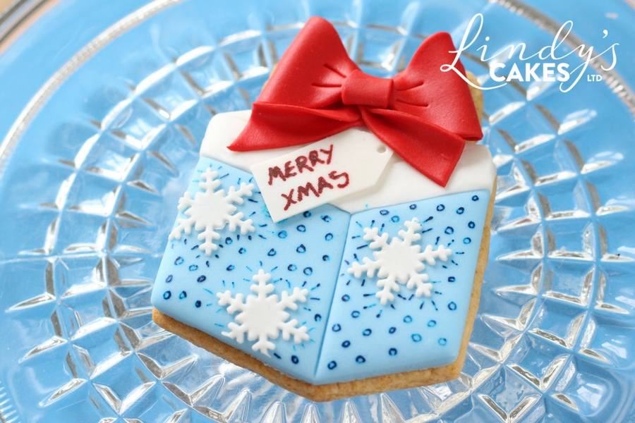 Christmas present cookie decorated with a fluid writer, snowflakes and a sugar bow